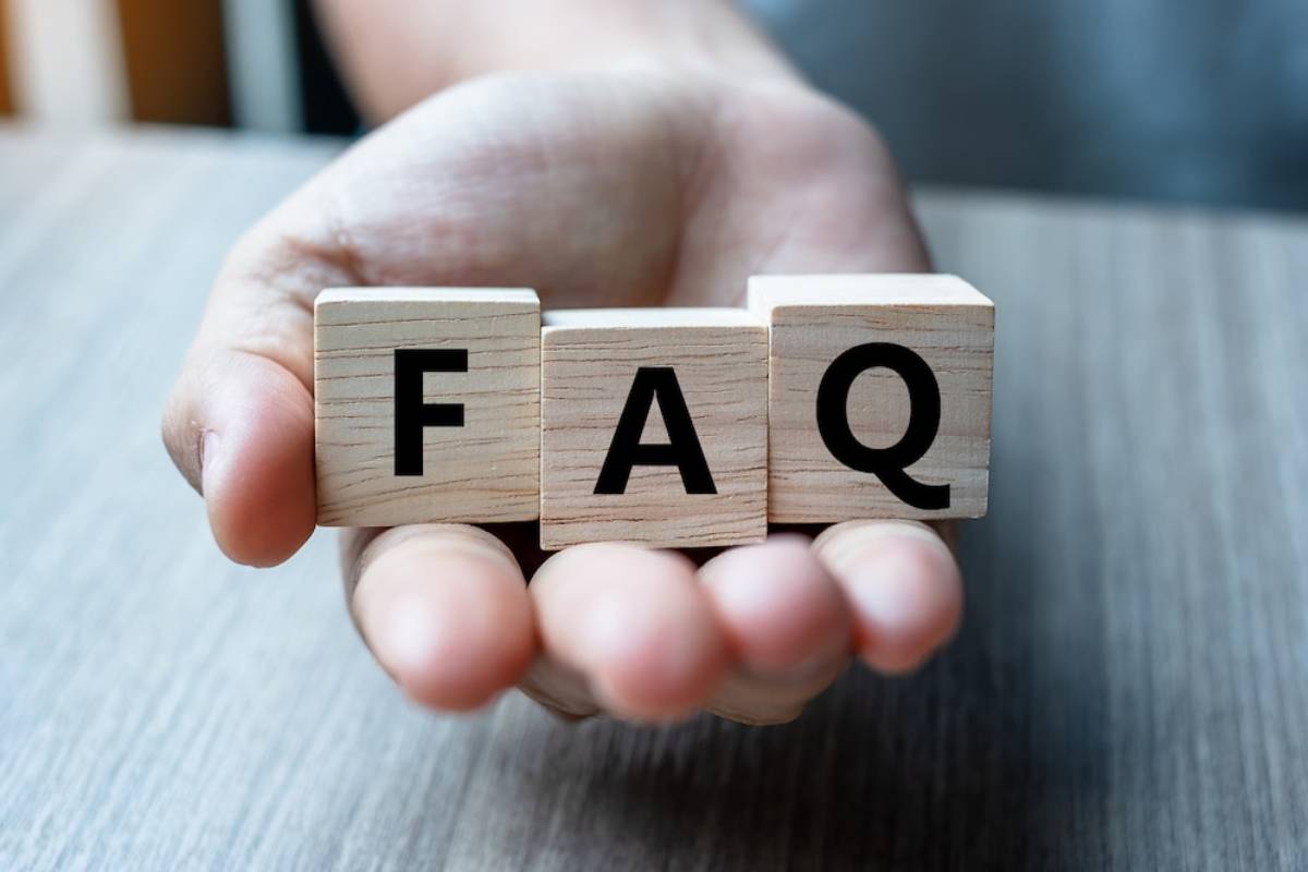A hand holds wooden blocks spelling FAQ against a blurred background, symbolizing frequently asked questions.